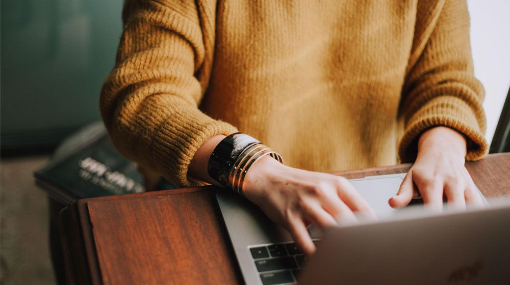 Woman sitting at a table using a laptop for online assessment