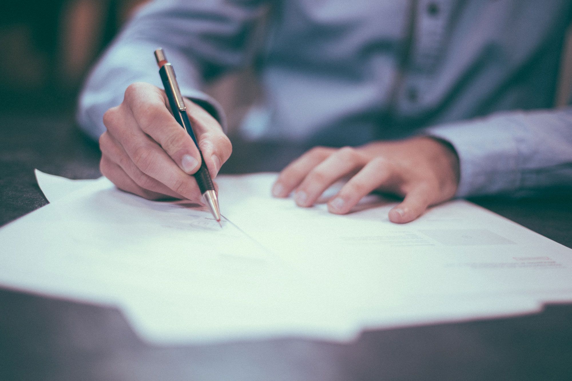 A man’s hands writing on paper