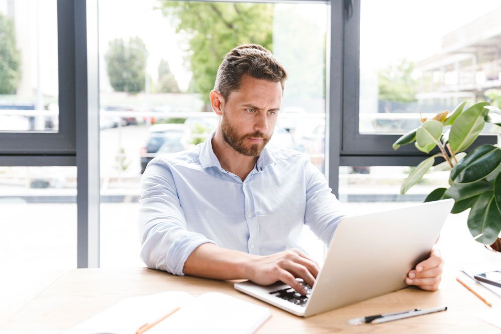 male-focusing-on-laptop-computer-screen-as-he-attends-his-online-exam