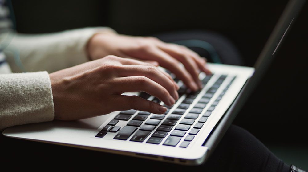 image of hands working on a laptop doing a remotely invigilated exam