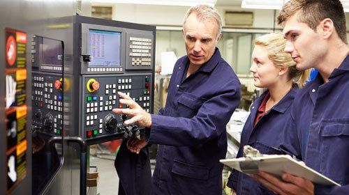 Two technical apprenticeship students being taught by older man